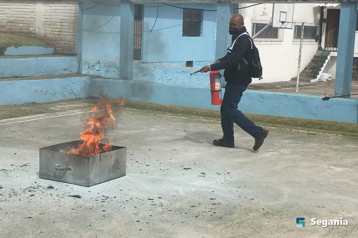 Trabajador acercándose con un extintor a un fuego controlado